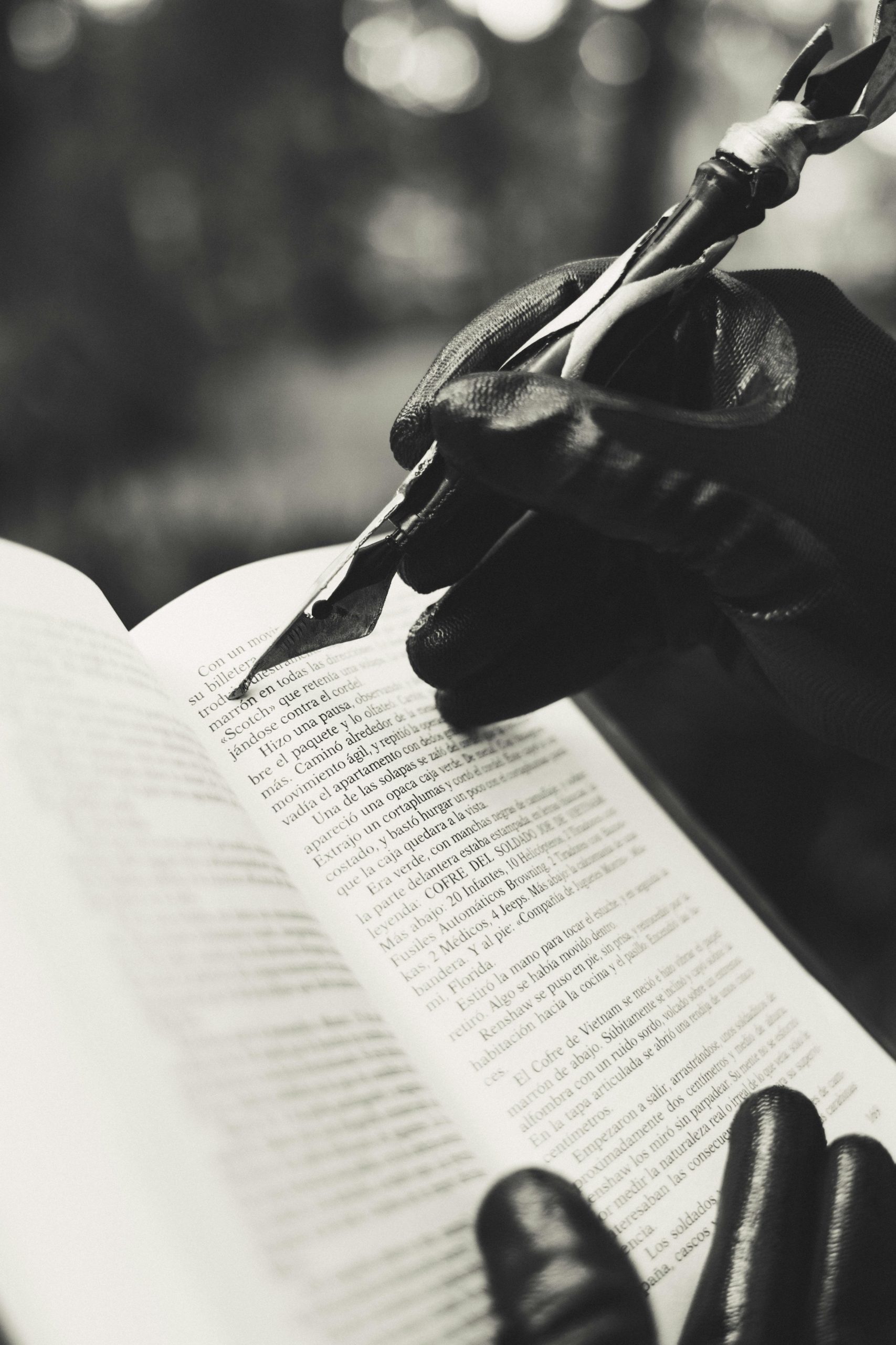 In this striking black and white image, gloved hands are writing in an open book with a feather pen, evoking a vintage and mysterious feel.